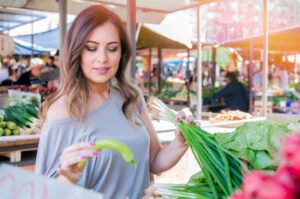 smiling woman with vegetable at market store. woman choosing fre